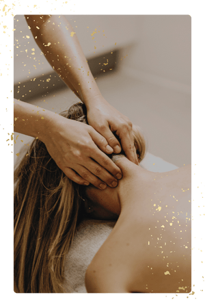 Massage therapist working on a woman's neck and shoulders, framed with gold splatter effects